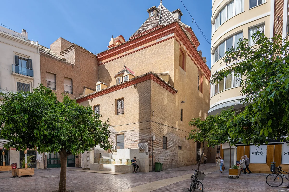 Plaza de las Flores in Málaga, a small square with orange trees and a brick church building in the middle