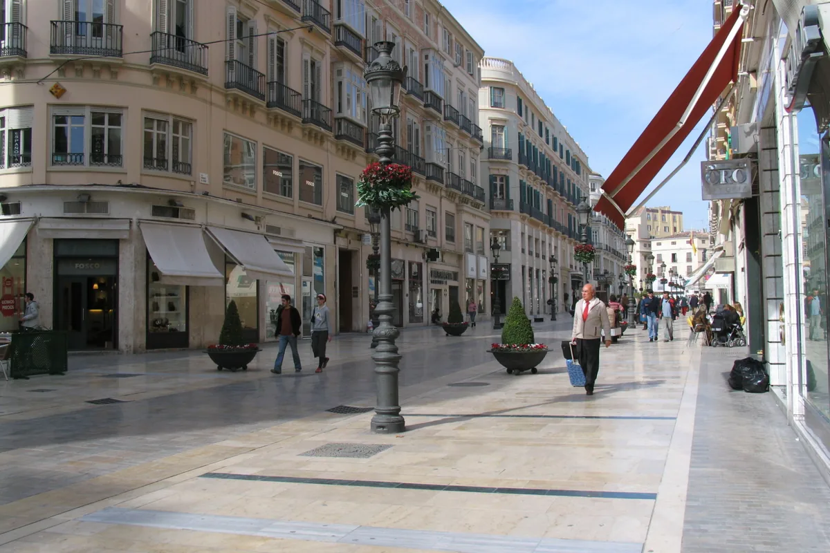 Calle Larios in Málaga, a wide pedestrian street of pale stone with tall balconied buildings and a lamp post hung with flowers